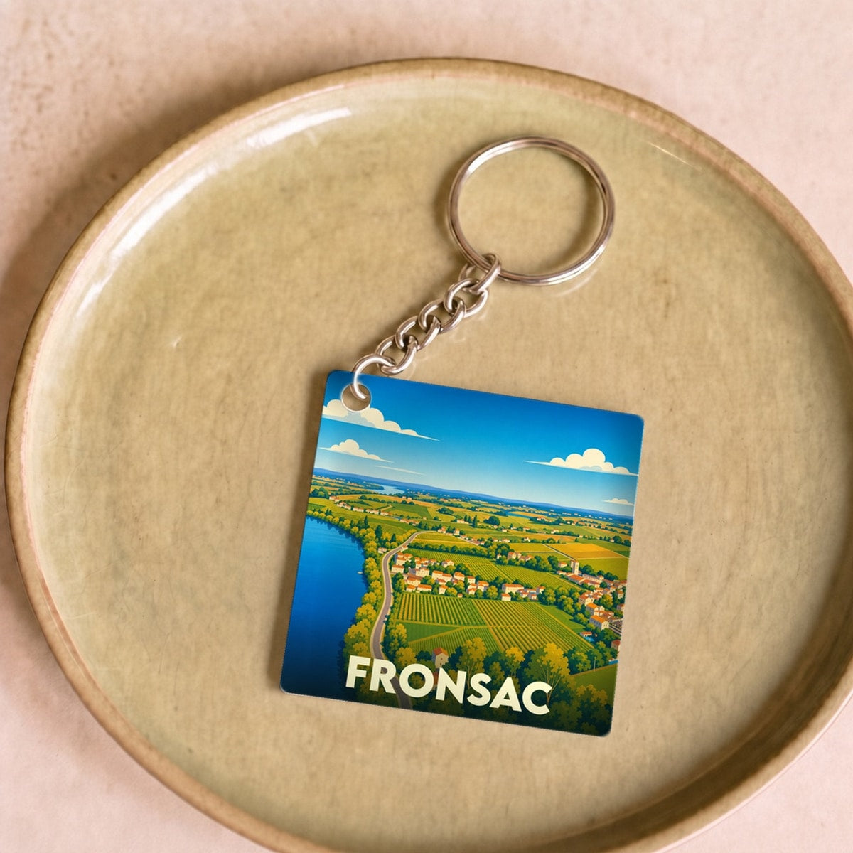 Porte-clés souvenir de la ville de Fronsac avec une illustration paysagère stylisée.