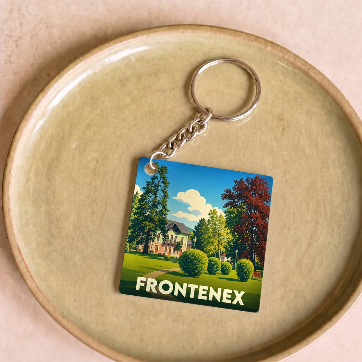 Porte-clés souvenir de la ville de Frontenex avec une illustration stylisée d'un parc paysager.