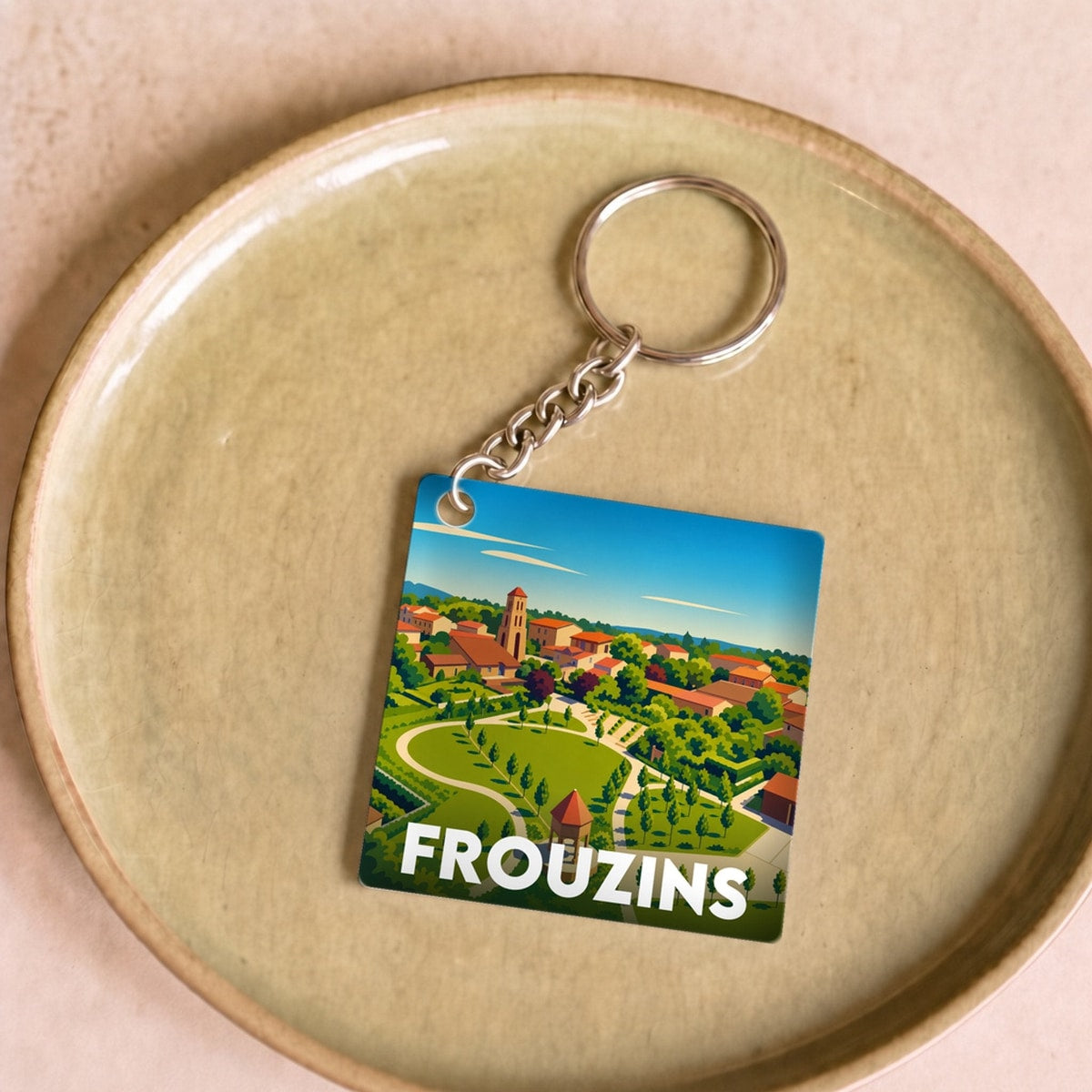 Porte-clés souvenir de la ville de Frouzins avec une illustration stylisée.