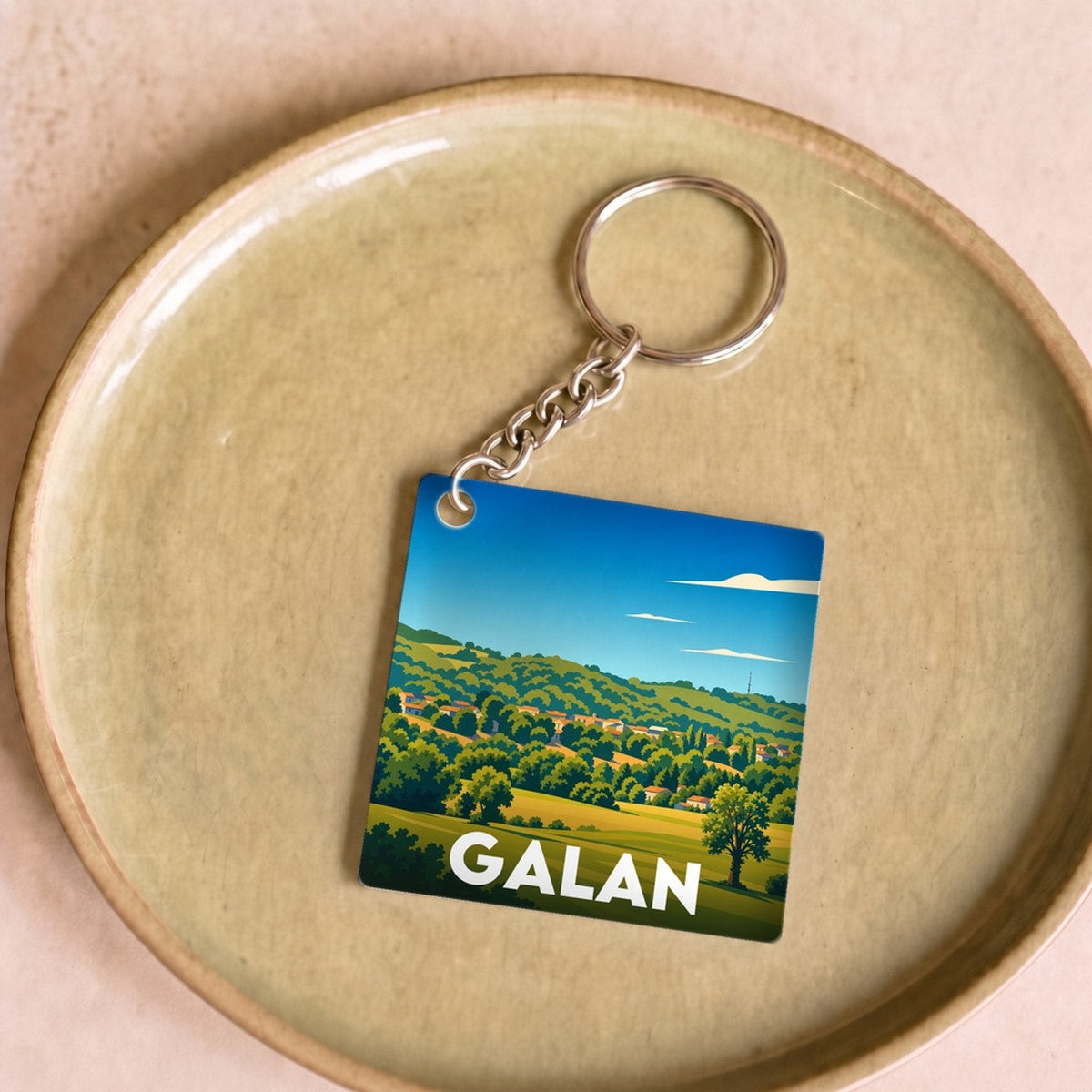 Porte-clés souvenir de la ville de Galan avec une illustration paysagère stylisée.
