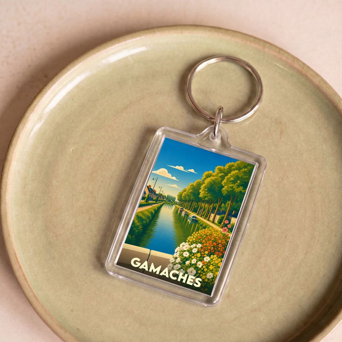Porte-clés souvenir de la ville de Gamaches avec une illustration stylisée d'un canal bordé d'arbres.