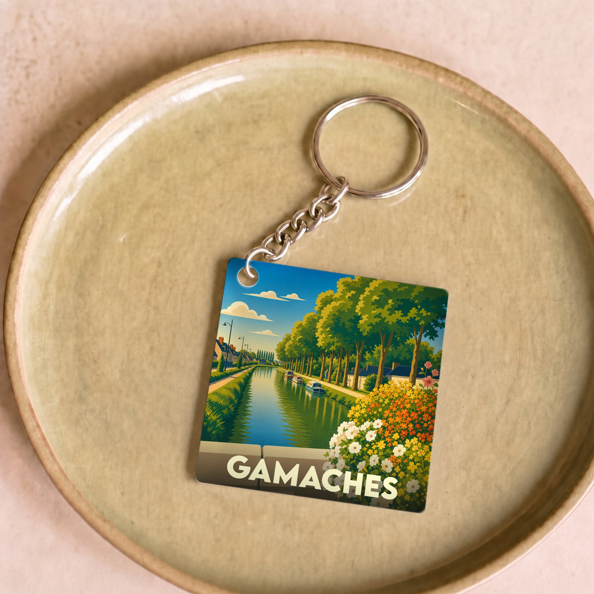 Porte-clés souvenir de la ville de Gamaches avec une illustration stylisée d'un canal bordé d'arbres.