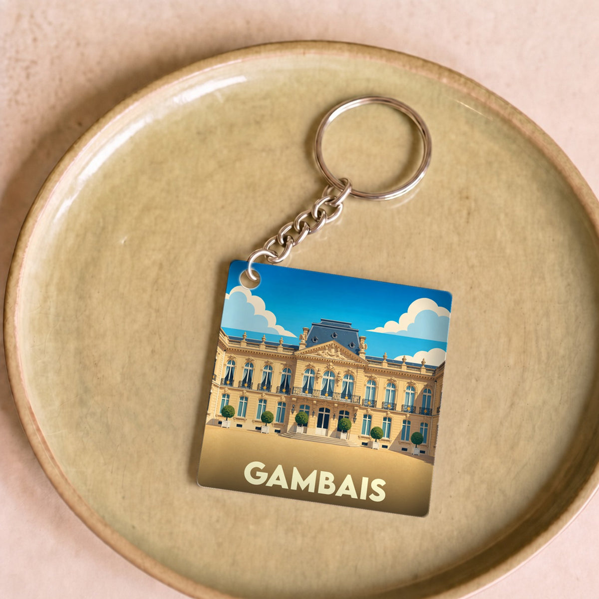 Porte-clés souvenir de la ville de Gambais avec une illustration stylisée d'un château.