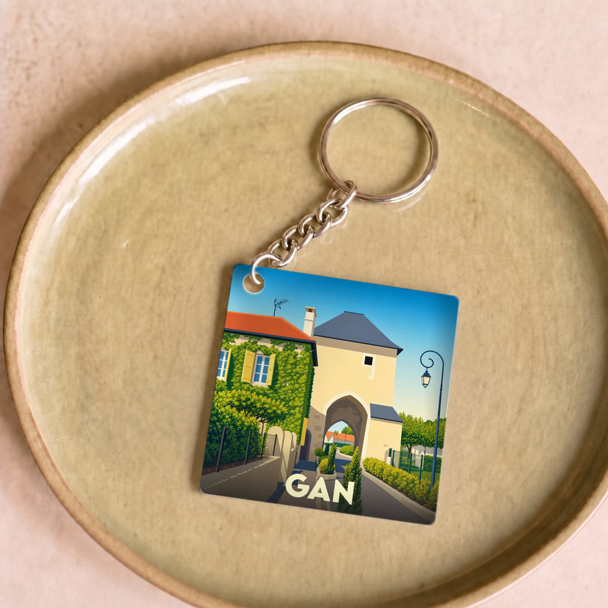 Porte-clés souvenir de la ville de Gan avec une illustration stylisée d'une porte historique.