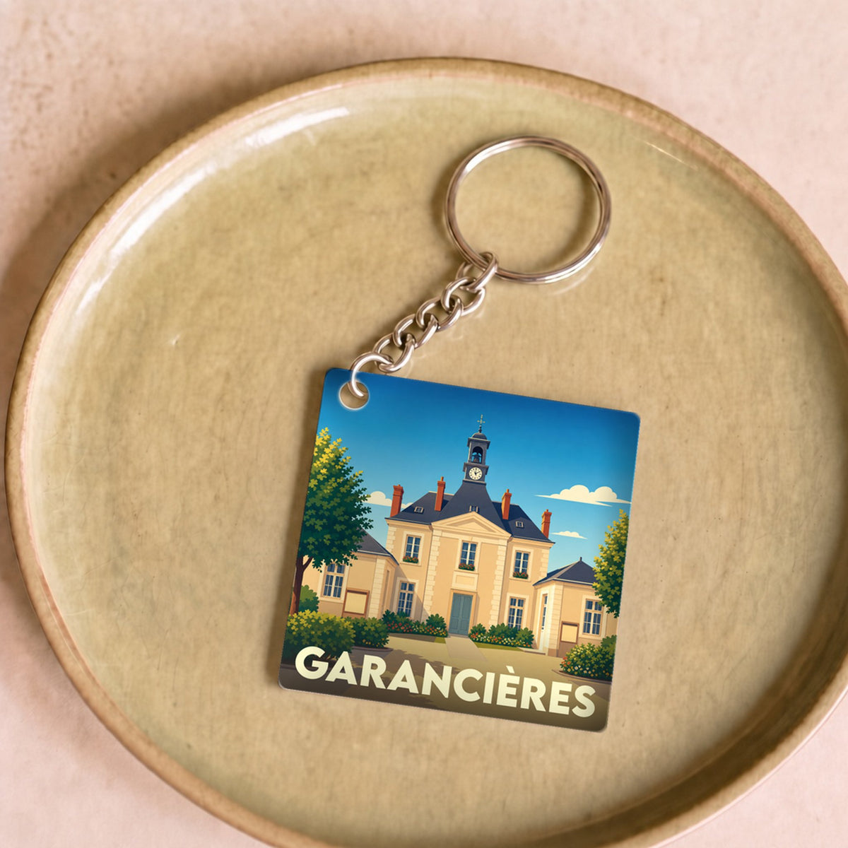 Porte-clés souvenir de la ville de Garancières avec une illustration stylisée de la mairie.