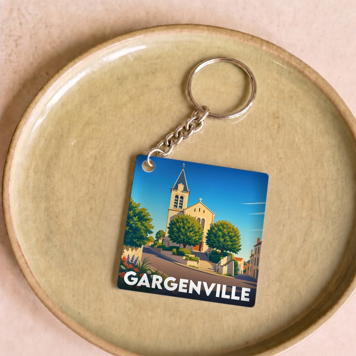Porte-clés souvenir de la ville de Gargenville avec une illustration stylisée d'une église sous un ciel bleu.