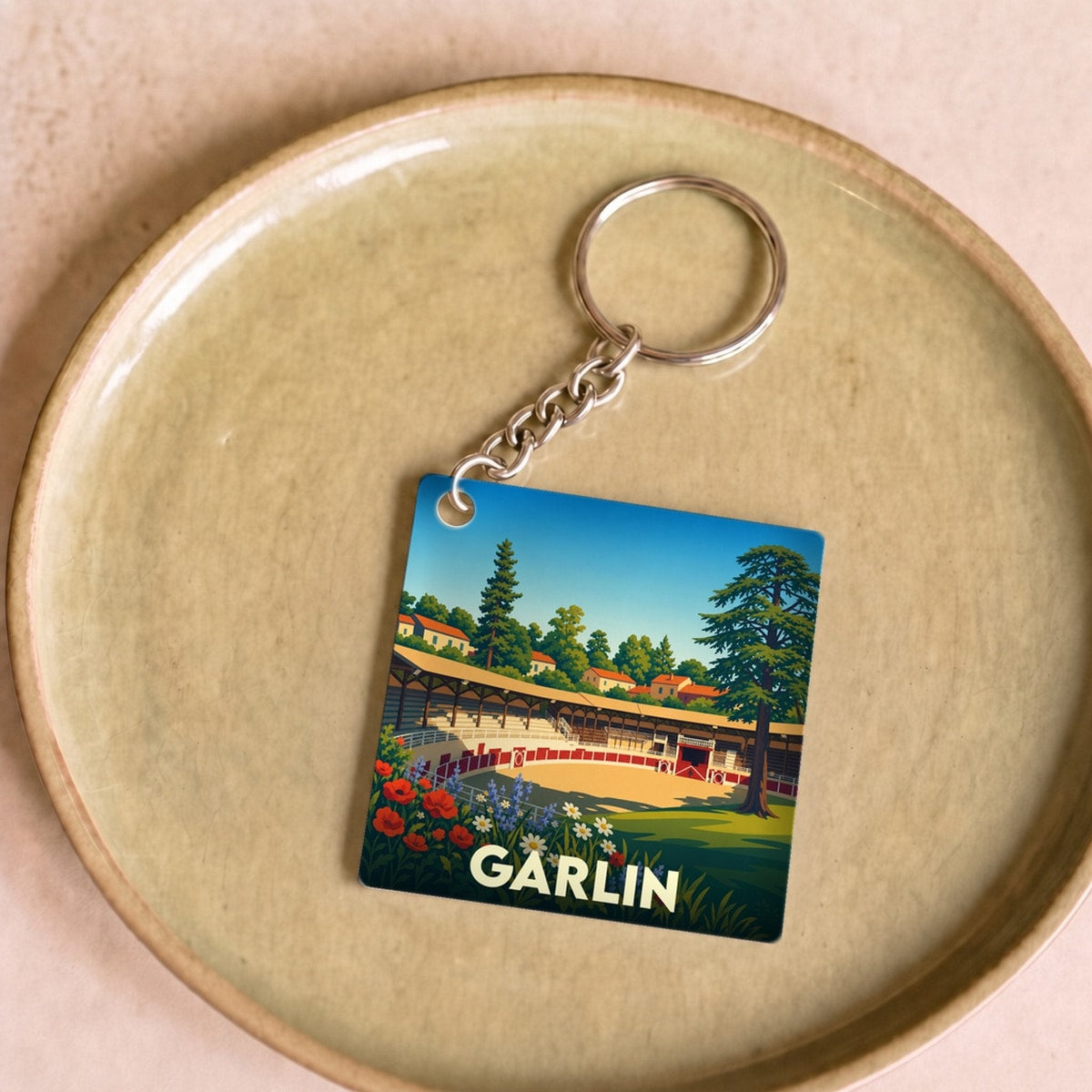 Porte-clés souvenir de la ville de Garlin avec une illustration stylisée de ses arènes.