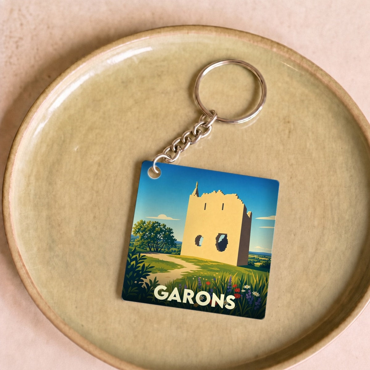 Porte-clés souvenir de la ville de Garons avec une illustration stylisée d'une tour historique.