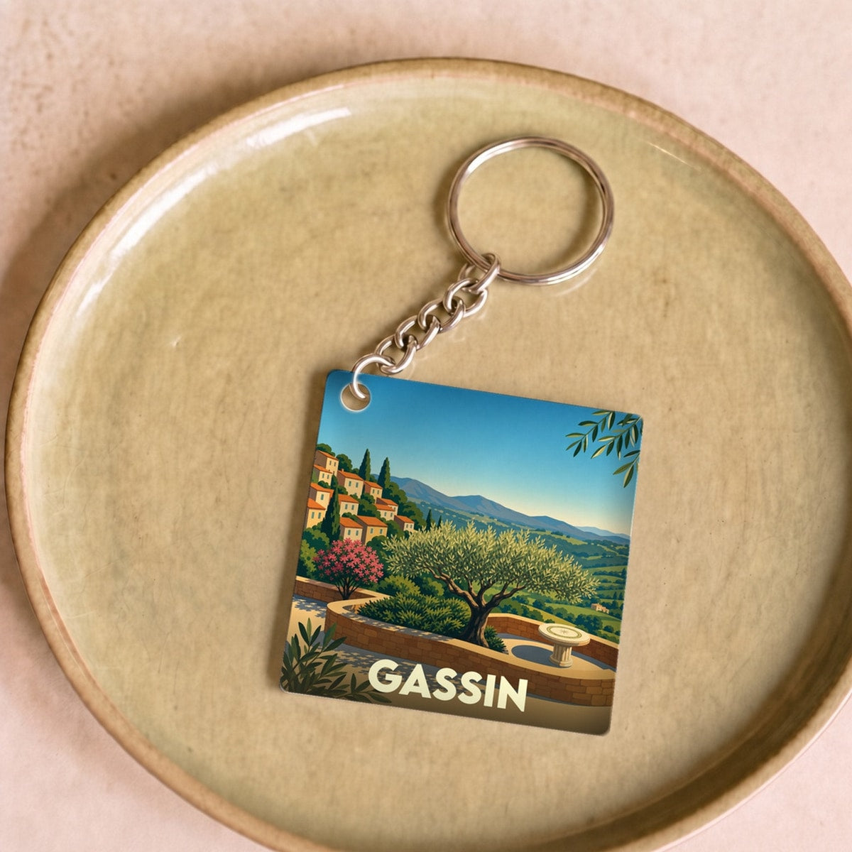 Porte-clés souvenir de la ville de Gassin avec une illustration stylisée d'un paysage provençal.
