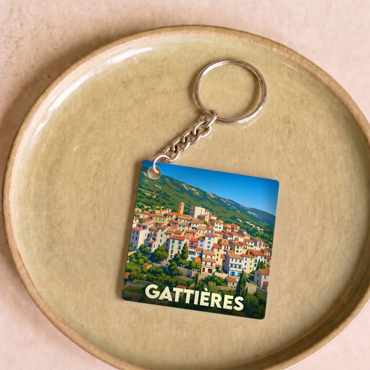Porte-clés souvenir de la ville de Gattières avec une illustration stylisée.