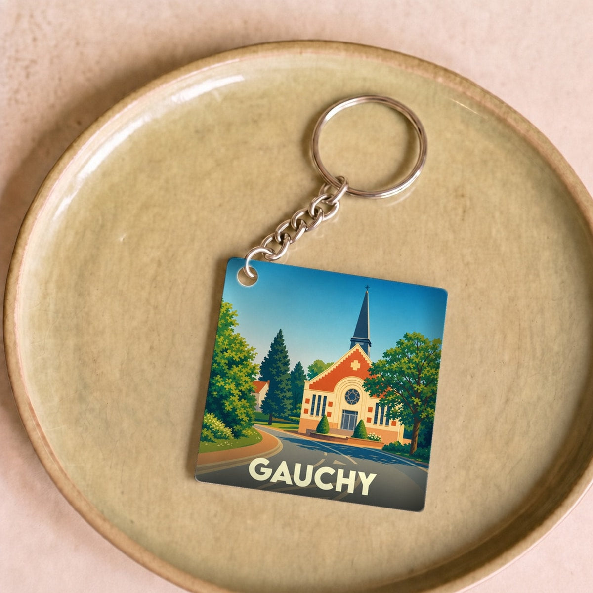 Porte-clés souvenir de la ville de Gauchy avec une illustration stylisée d'une église sous un ciel bleu.