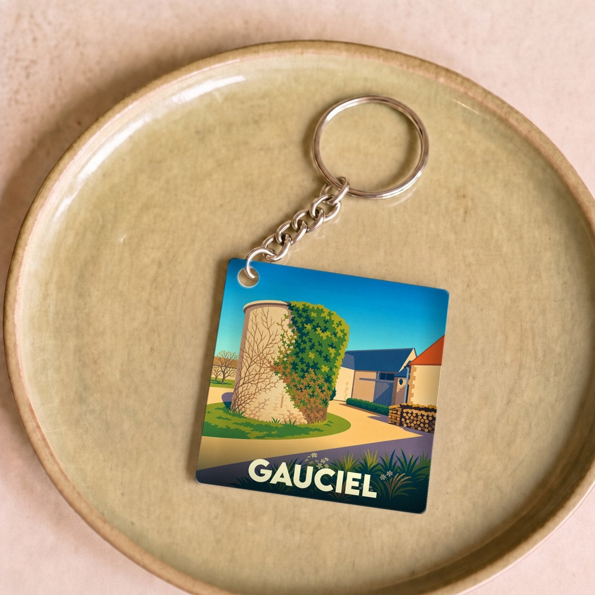 Porte-clés souvenir de la ville de Gauciel avec une illustration stylisée d'une tour en pierre.