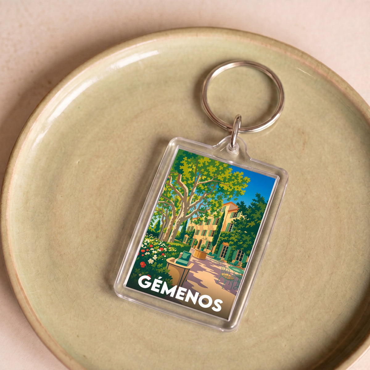Porte-clés souvenir de la ville de Gémenos avec une illustration stylisée.