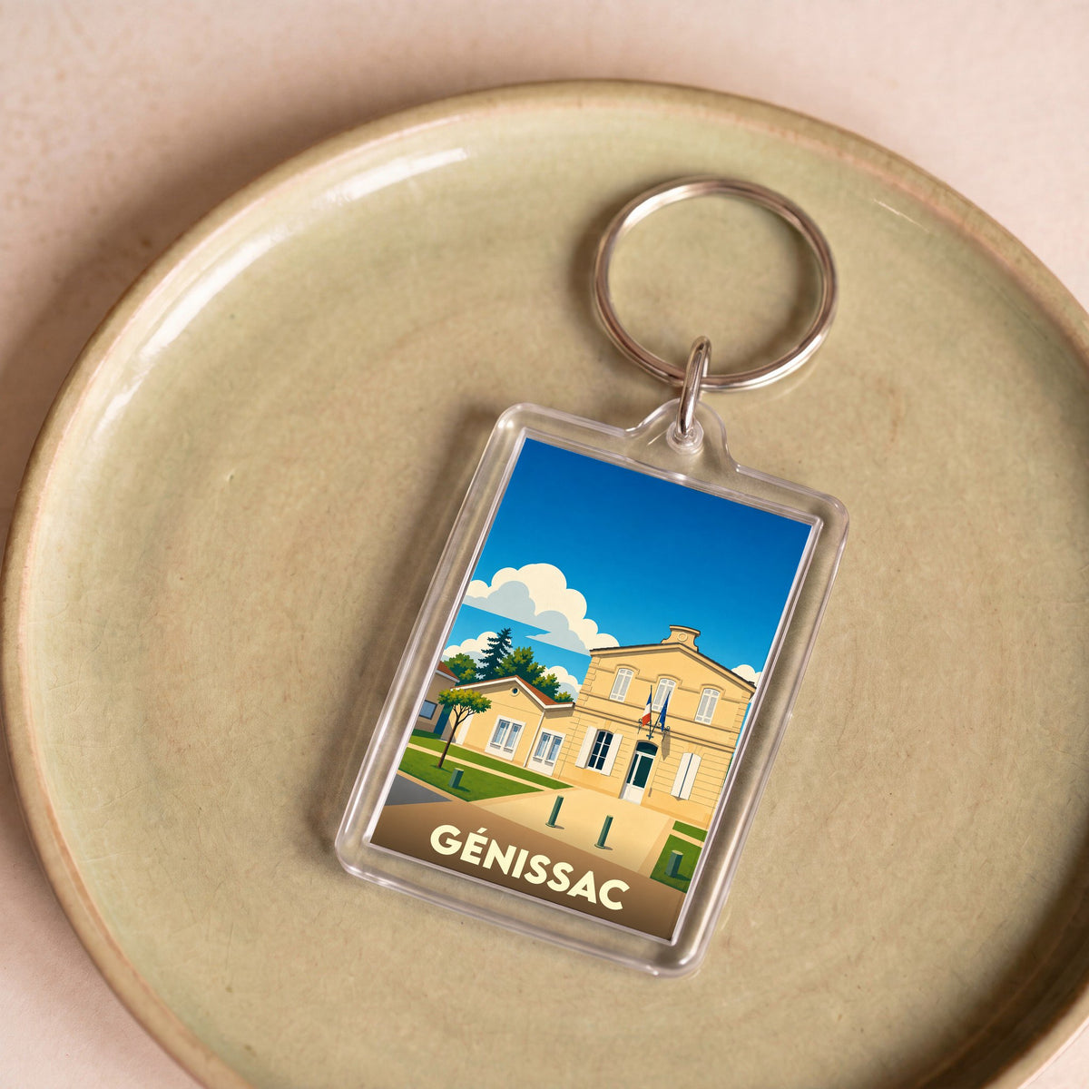 Porte-clés souvenir de la ville de Génissac avec une illustration stylisée de sa mairie.