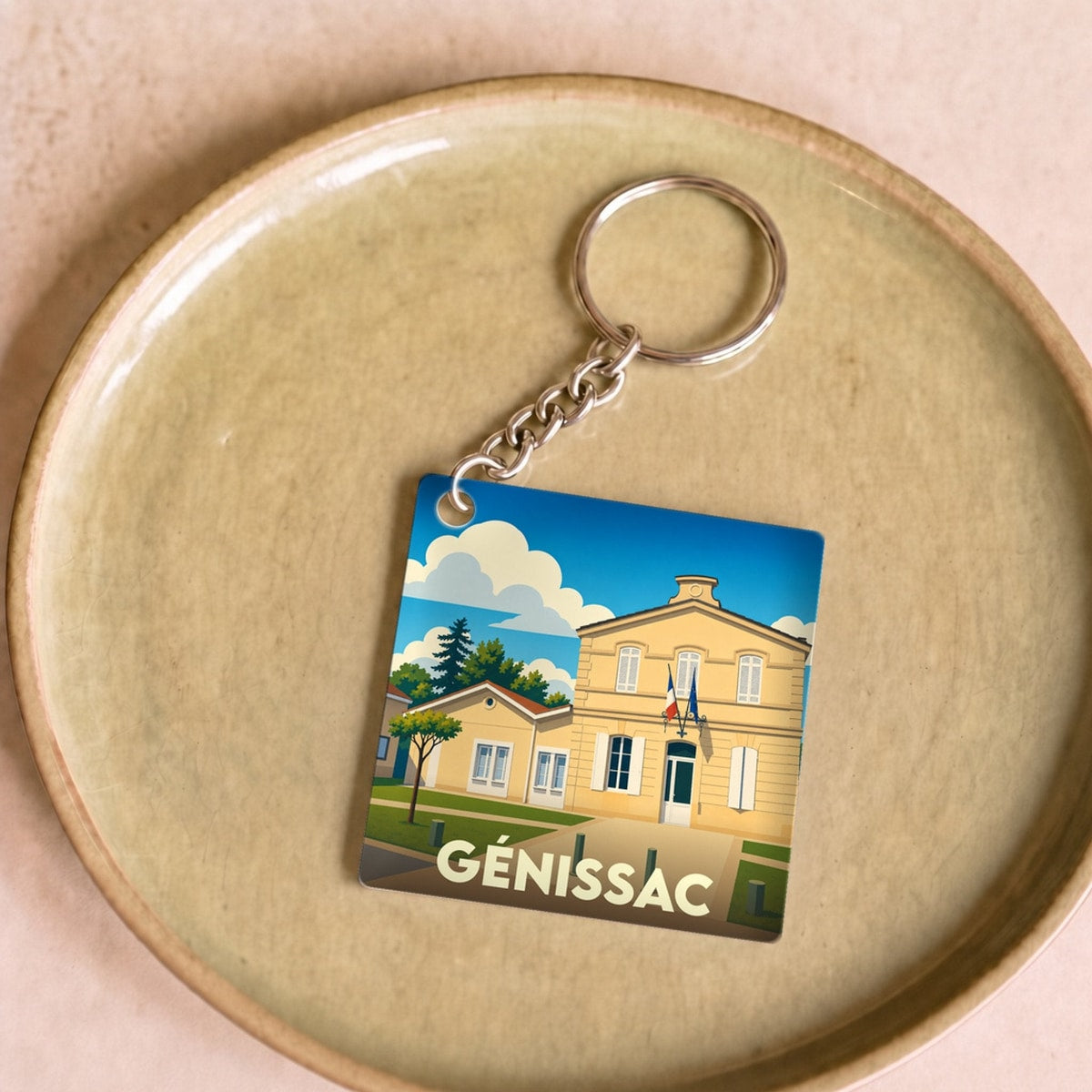 Porte-clés souvenir de la ville de Génissac avec une illustration stylisée de sa mairie.