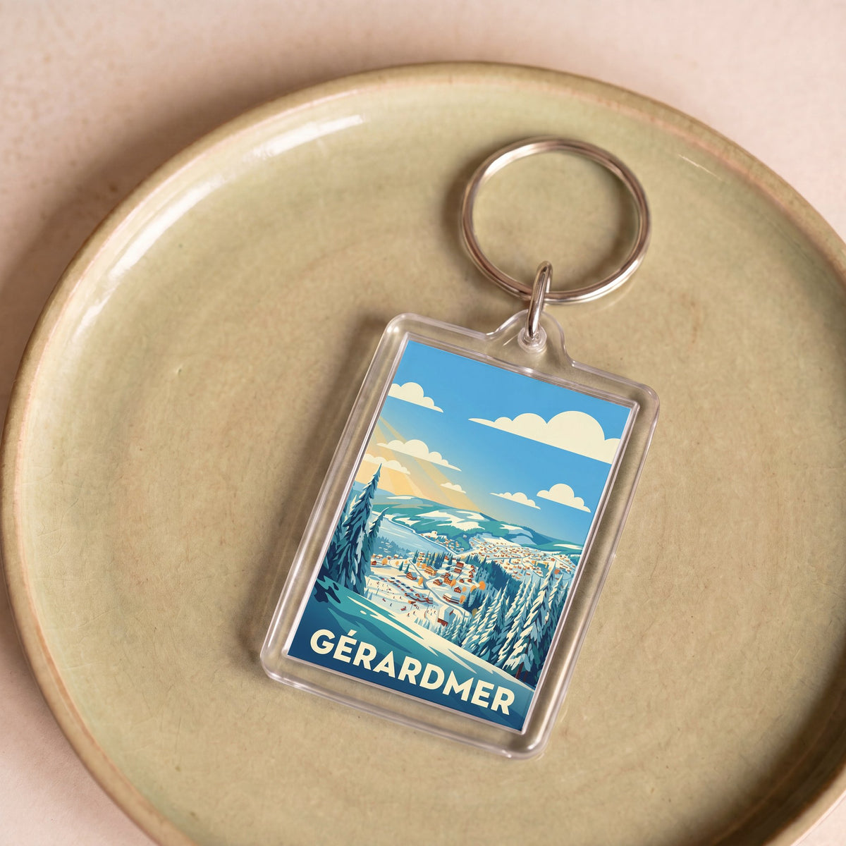 Porte-clés souvenir de la ville de Gérardmer avec une illustration hivernale stylisée.