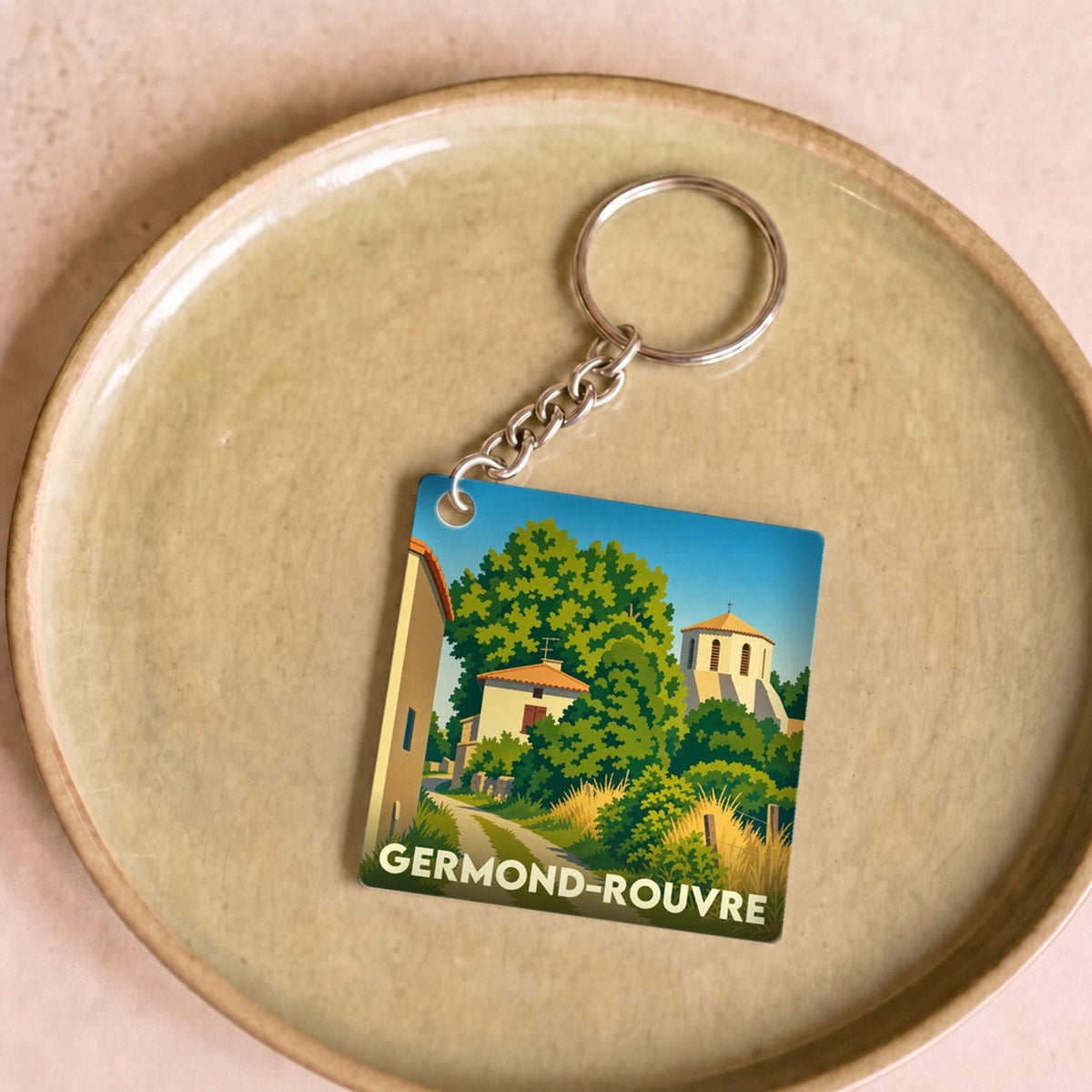 Porte-clés souvenir de la ville de Germond-Rouvre avec une illustration stylisée d'un paysage de village.