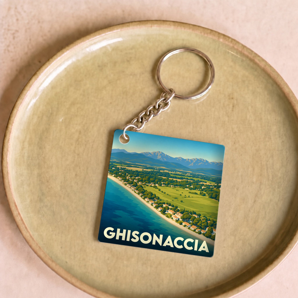 Porte-clés souvenir de la ville de Ghisonaccia avec une illustration stylisée de son littoral et des montagnes.