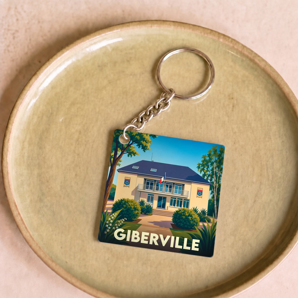 Porte-clés souvenir de la ville de Giberville avec une illustration stylisée de sa mairie.