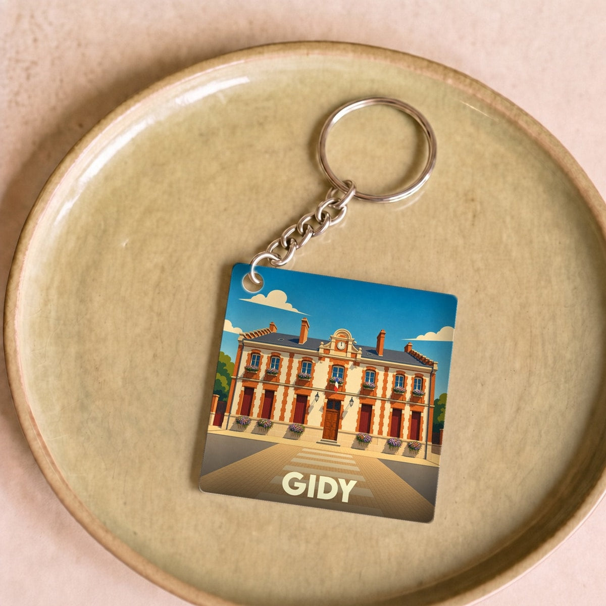 Porte-clés souvenir de la ville de Gidy avec une illustration stylisée de sa mairie.