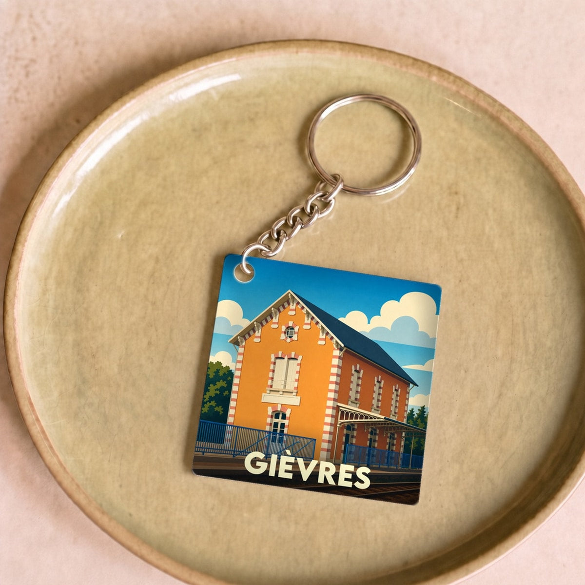 Porte-clés souvenir de la ville de Gièvres avec une illustration stylisée de sa gare ferroviaire.