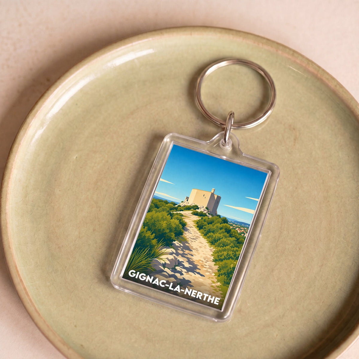 Porte-clés souvenir de Gignac-la-Nerthe avec une illustration stylisée d'un paysage provençal.