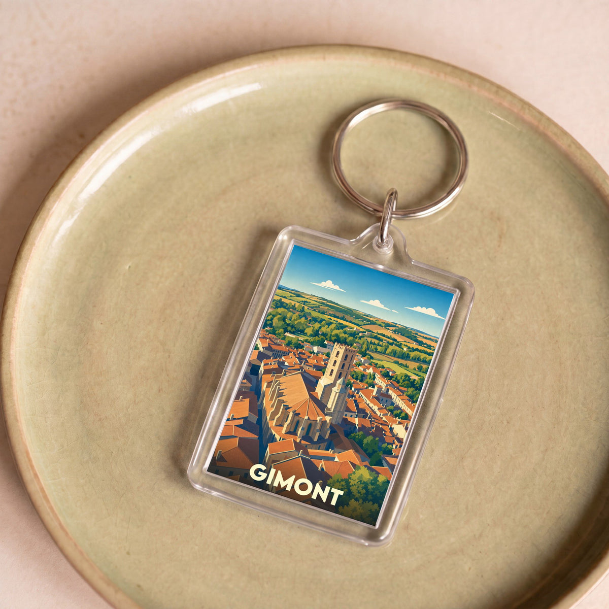 Porte-clés souvenir de la ville de Gimont avec une illustration stylisée.
