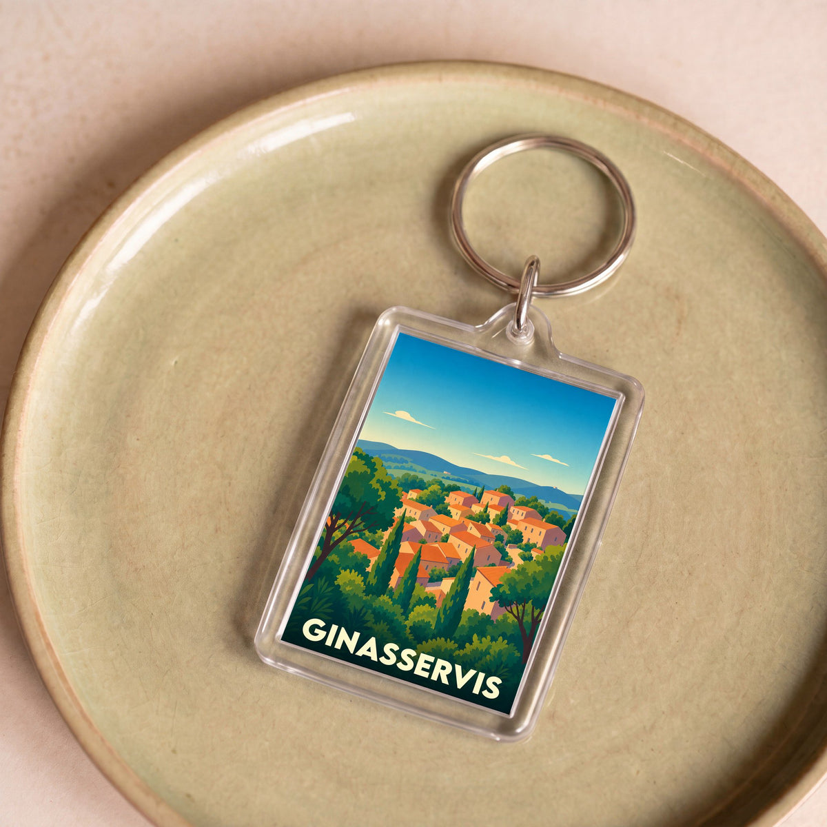 Porte-clés souvenir de la ville de Ginasservis avec une illustration stylisée de son village provençal.