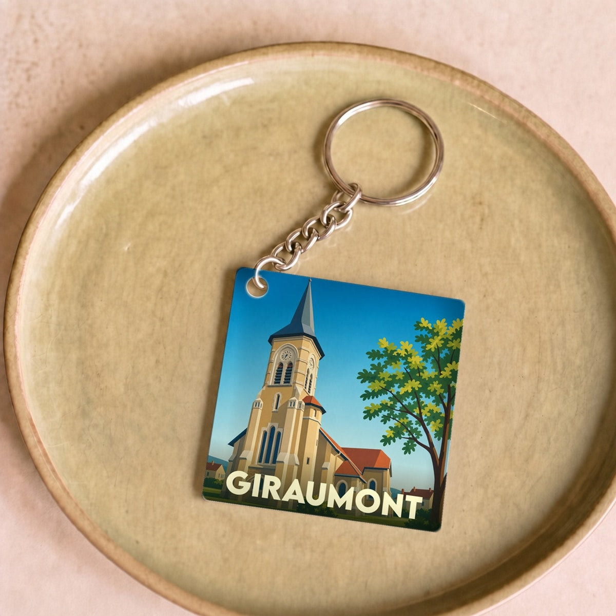 Porte-clés souvenir de la ville de Giraumont avec une illustration stylisée de son église.