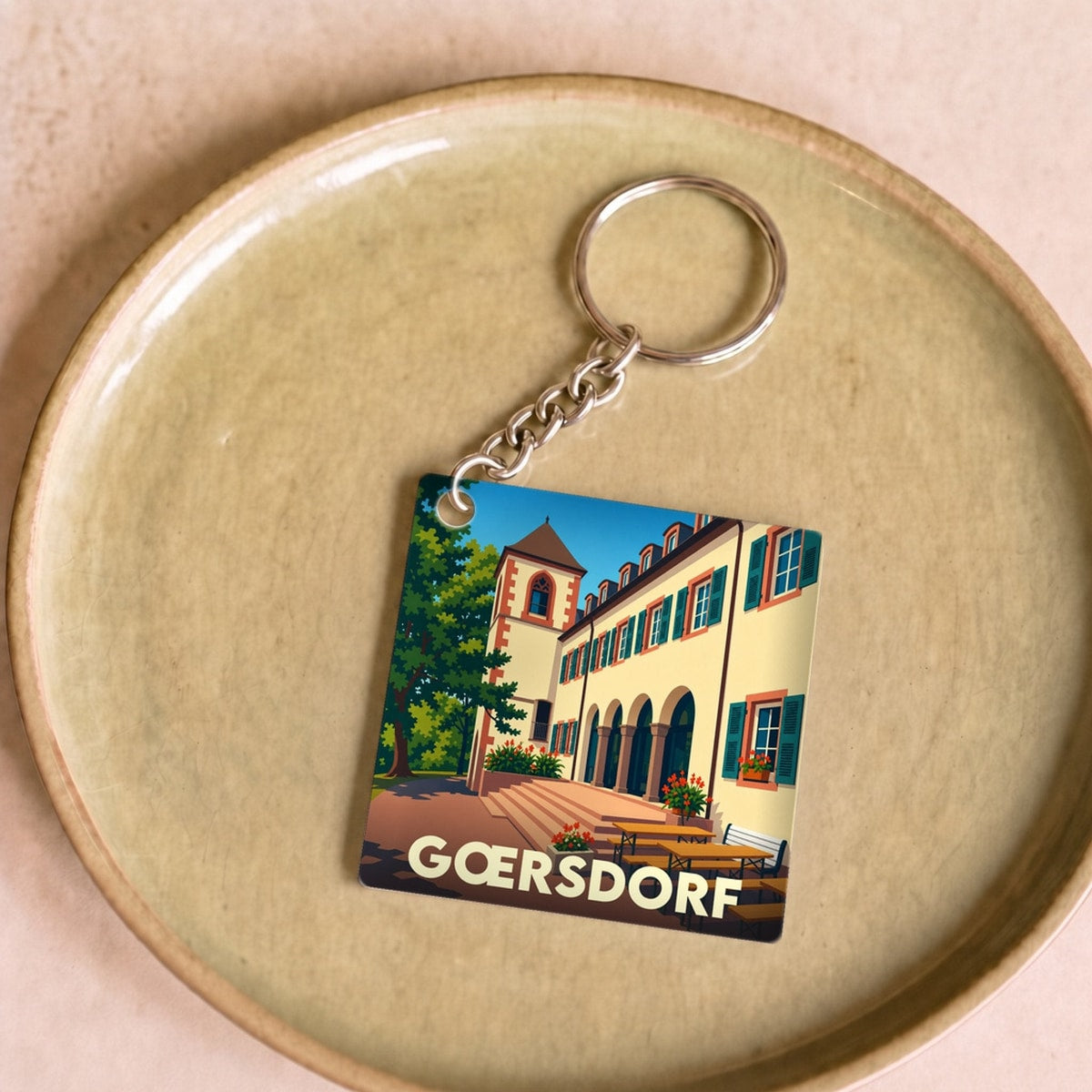 Porte-clés souvenir de la ville de Gœrsdorf avec une illustration stylisée.