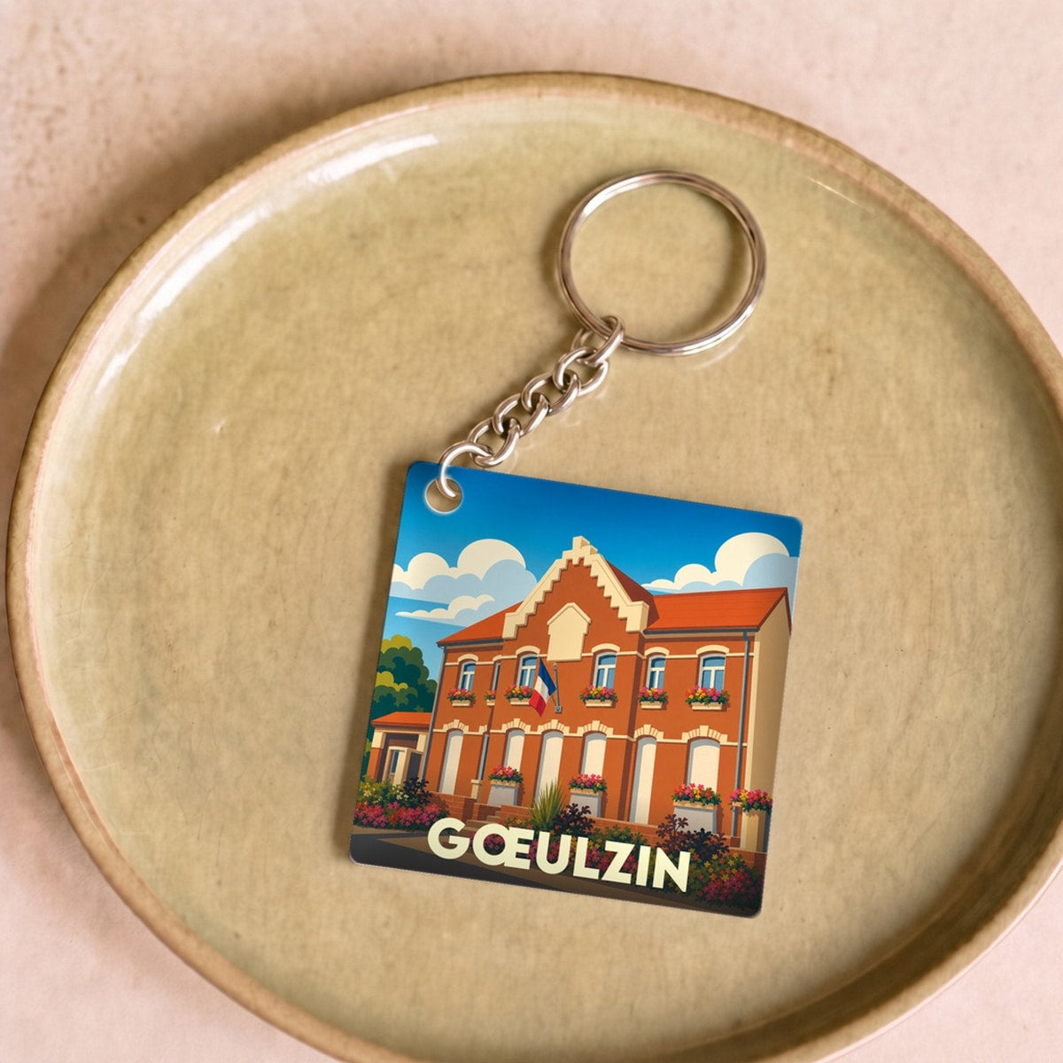 Porte-clés souvenir de la ville de Gœulzin avec une illustration stylisée de sa mairie.