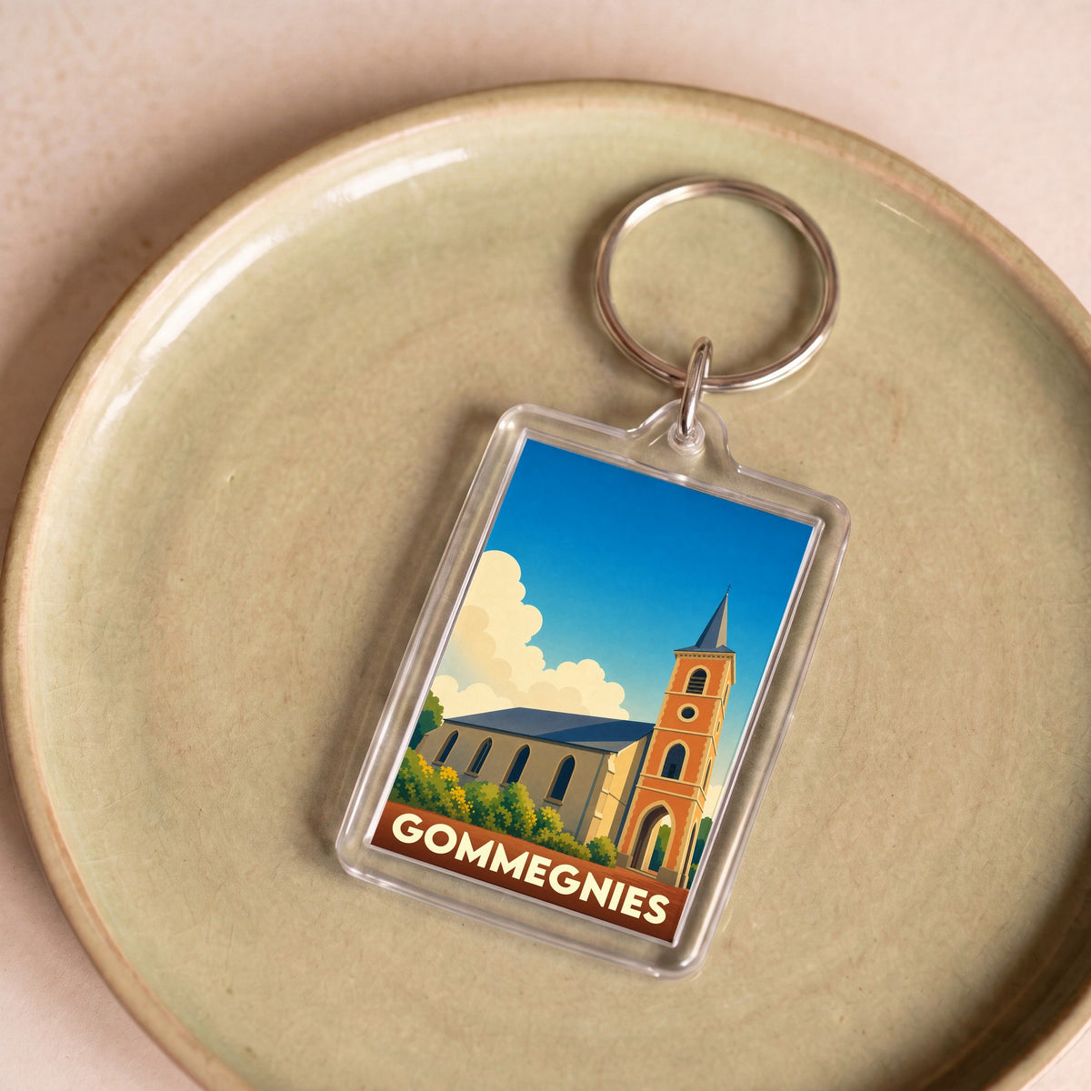 Porte-clés souvenir de la ville de Gommegnies avec une illustration stylisée de son église.