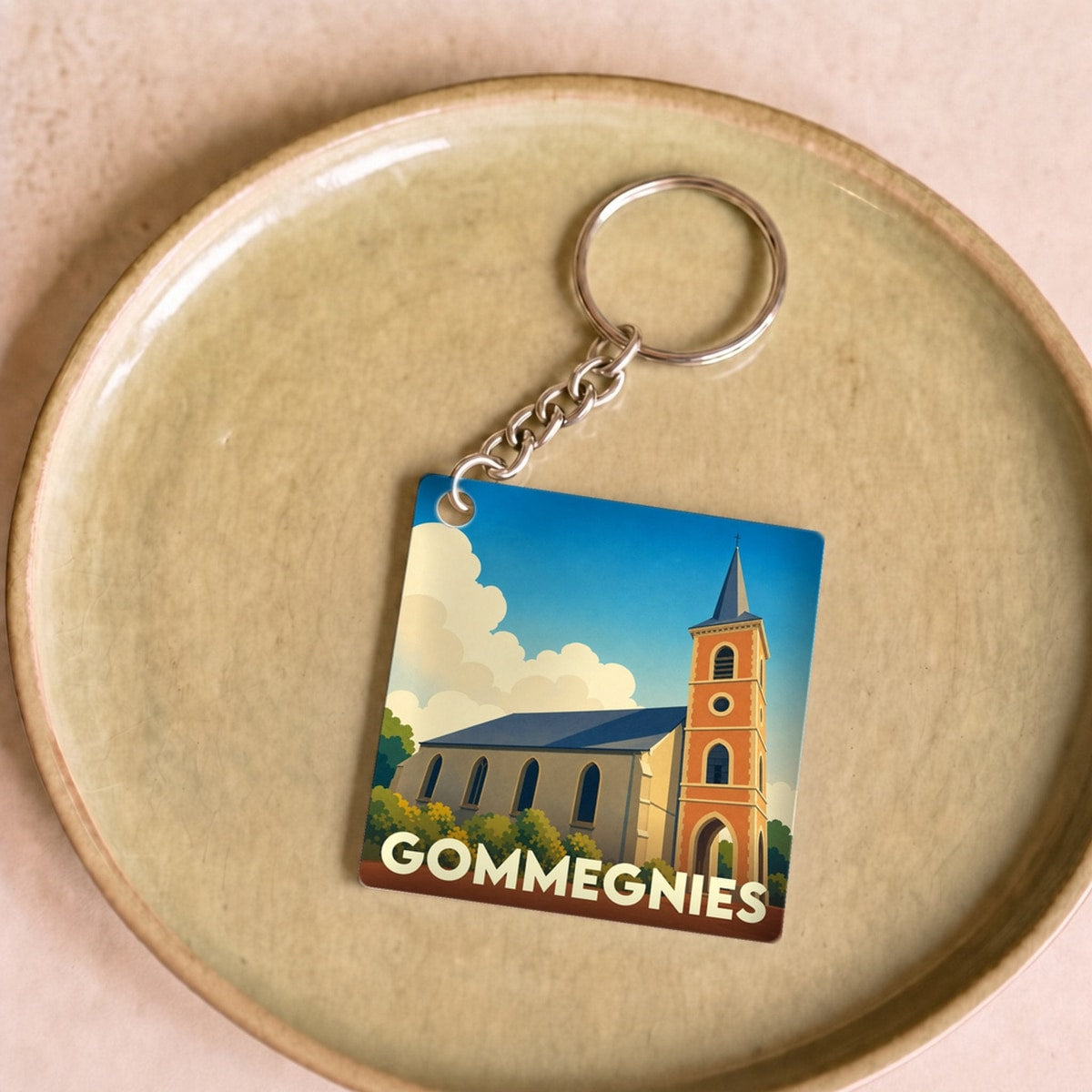 Porte-clés souvenir de la ville de Gommegnies avec une illustration stylisée de son église.