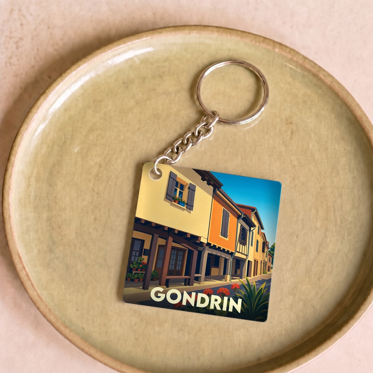 Porte-clés souvenir de la ville de Gondrin avec une illustration stylisée de ses façades colorées.