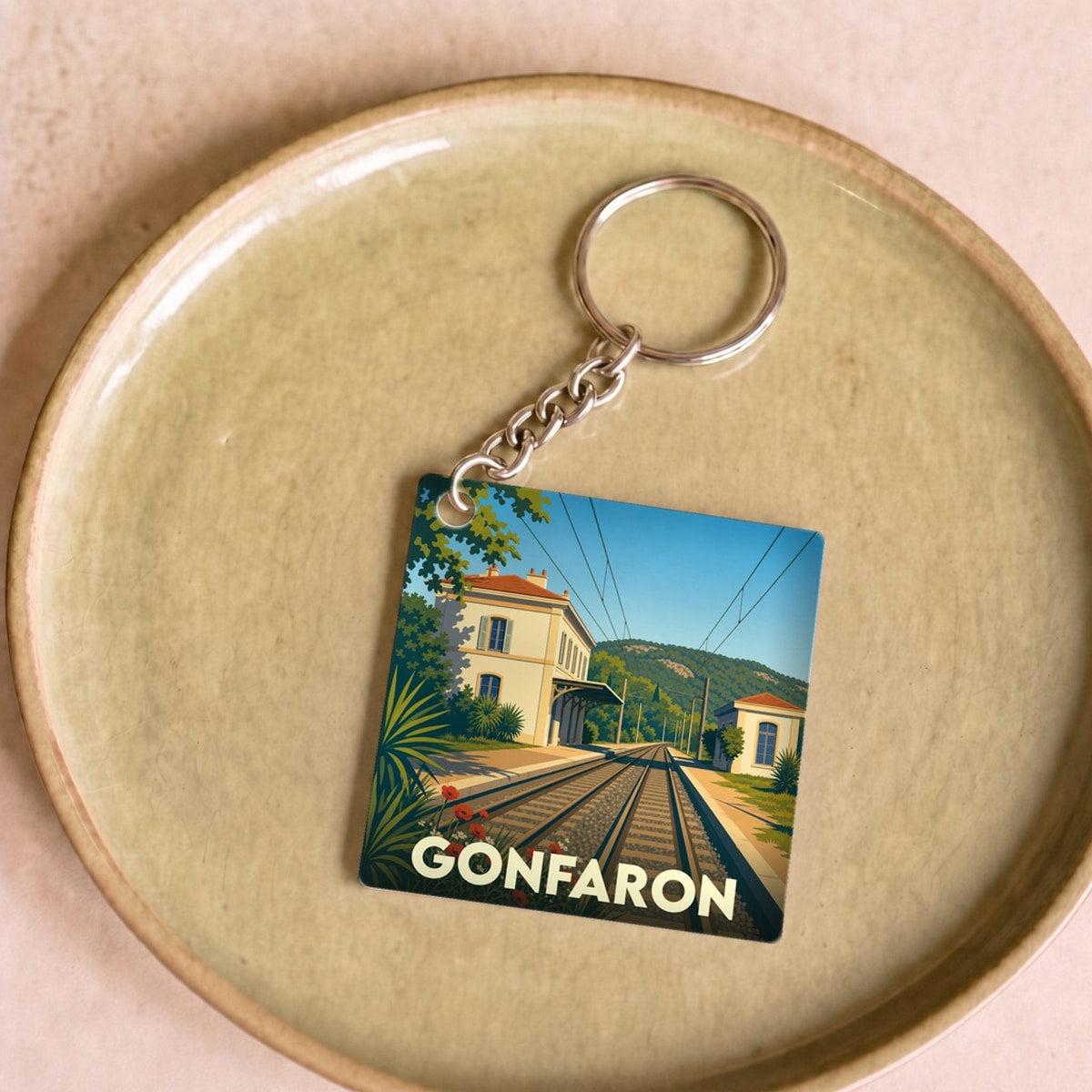 Porte-clés souvenir de la ville de Gonfaron avec une illustration stylisée d'une gare ferroviaire.