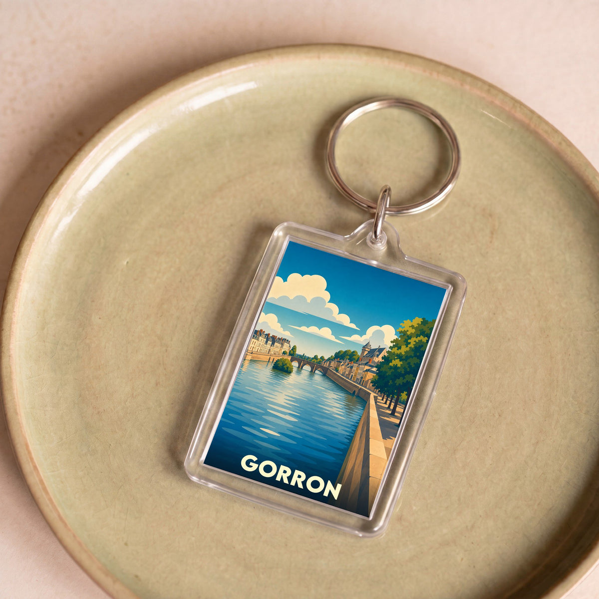 Porte-clés souvenir de la ville de Gorron avec une illustration stylisée d'un paysage fluvial.