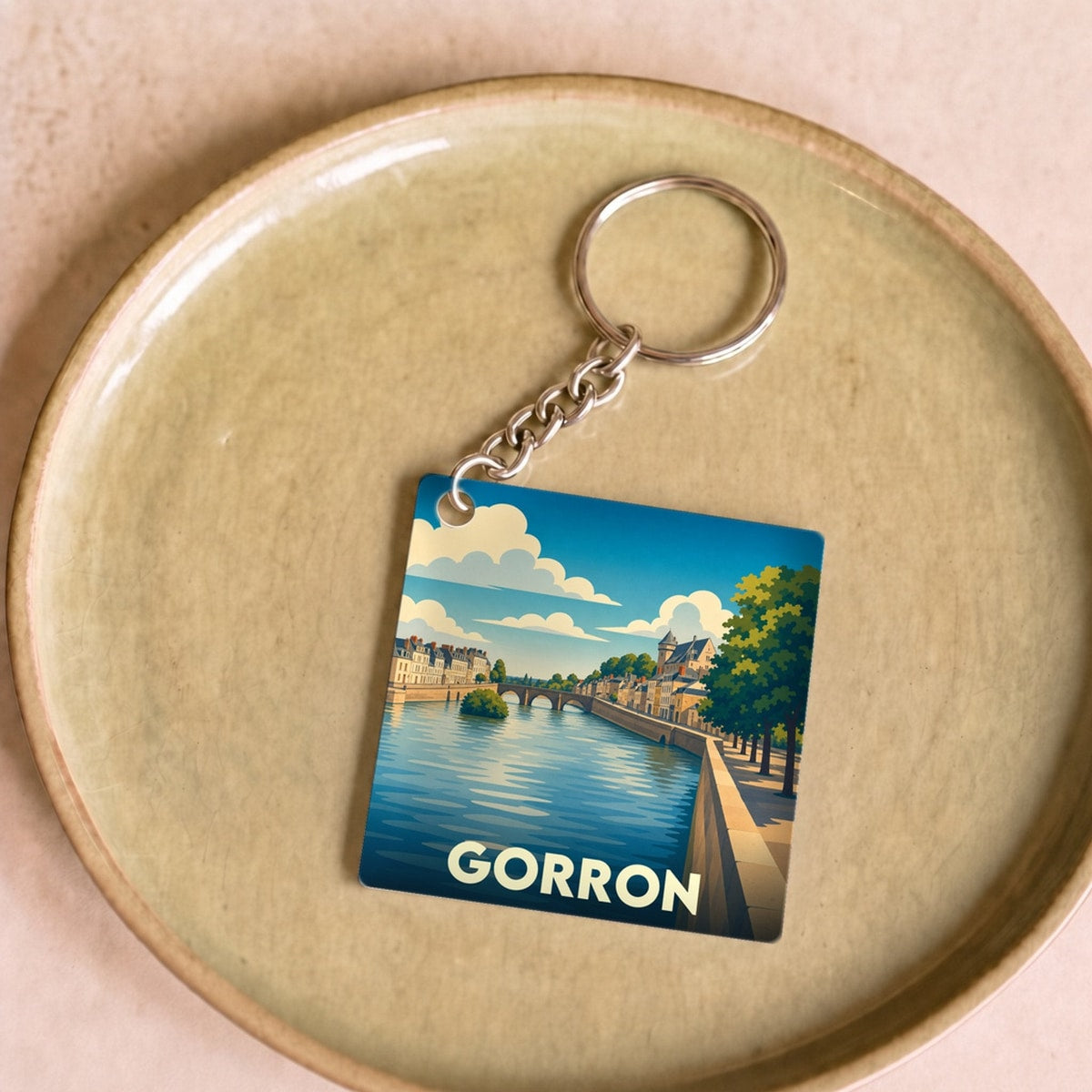 Porte-clés souvenir de la ville de Gorron avec une illustration stylisée d'un paysage fluvial.