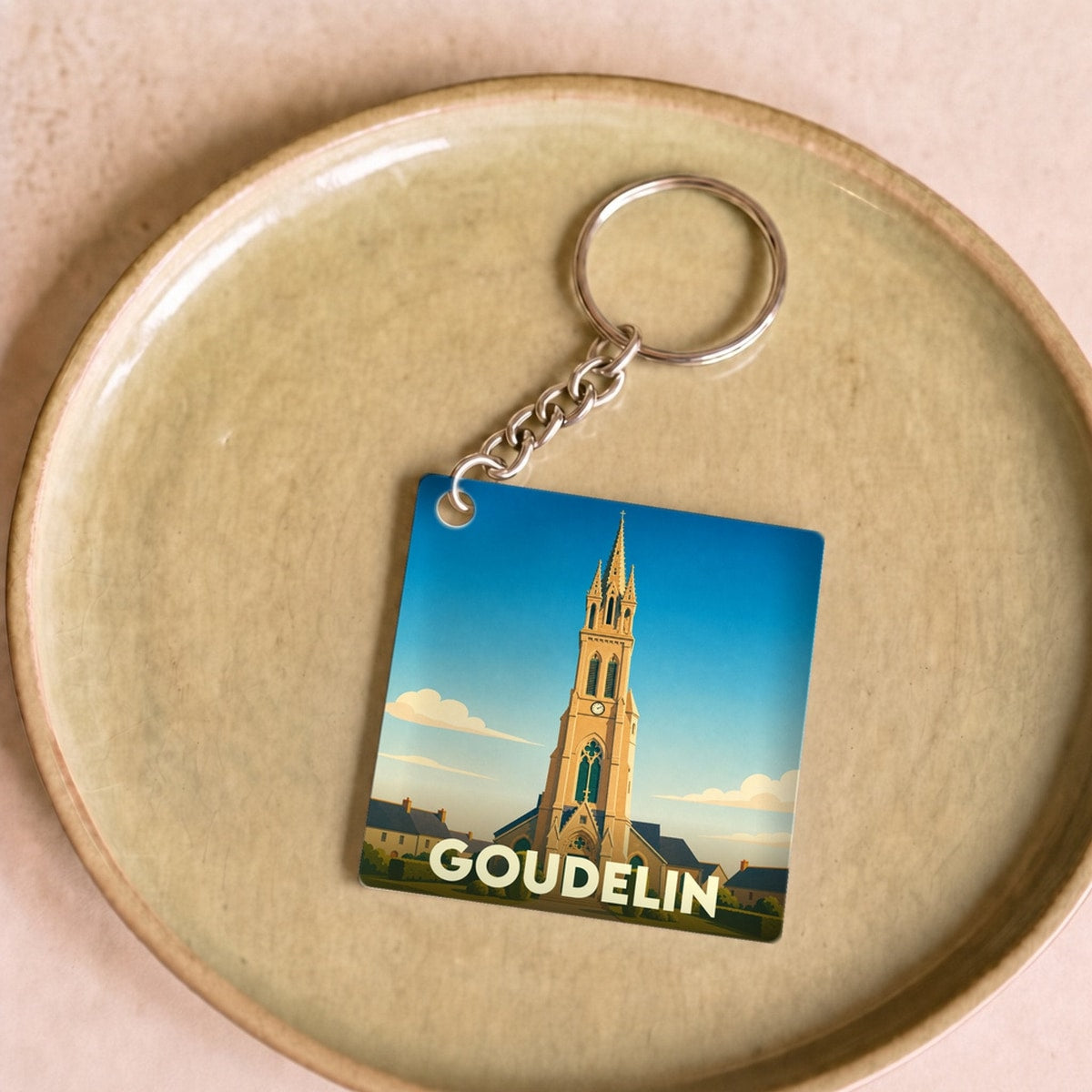 Porte-clés souvenir de la ville de Goudelin avec une illustration stylisée de son église.