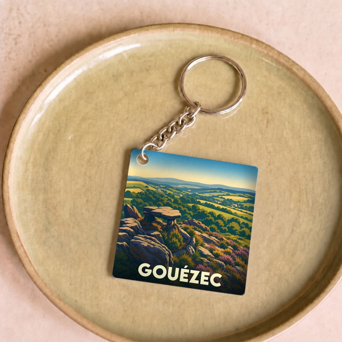 Porte-clés souvenir de la ville de Gouézec avec une illustration stylisée de son paysage vallonné.