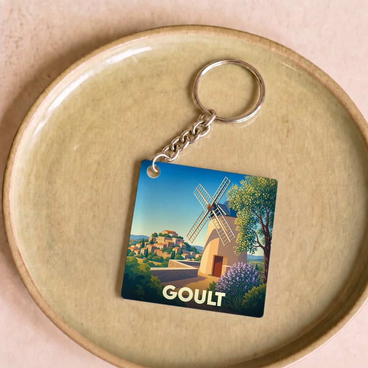 Porte-clés souvenir de la ville de Goult avec une illustration stylisée de son moulin et du village.