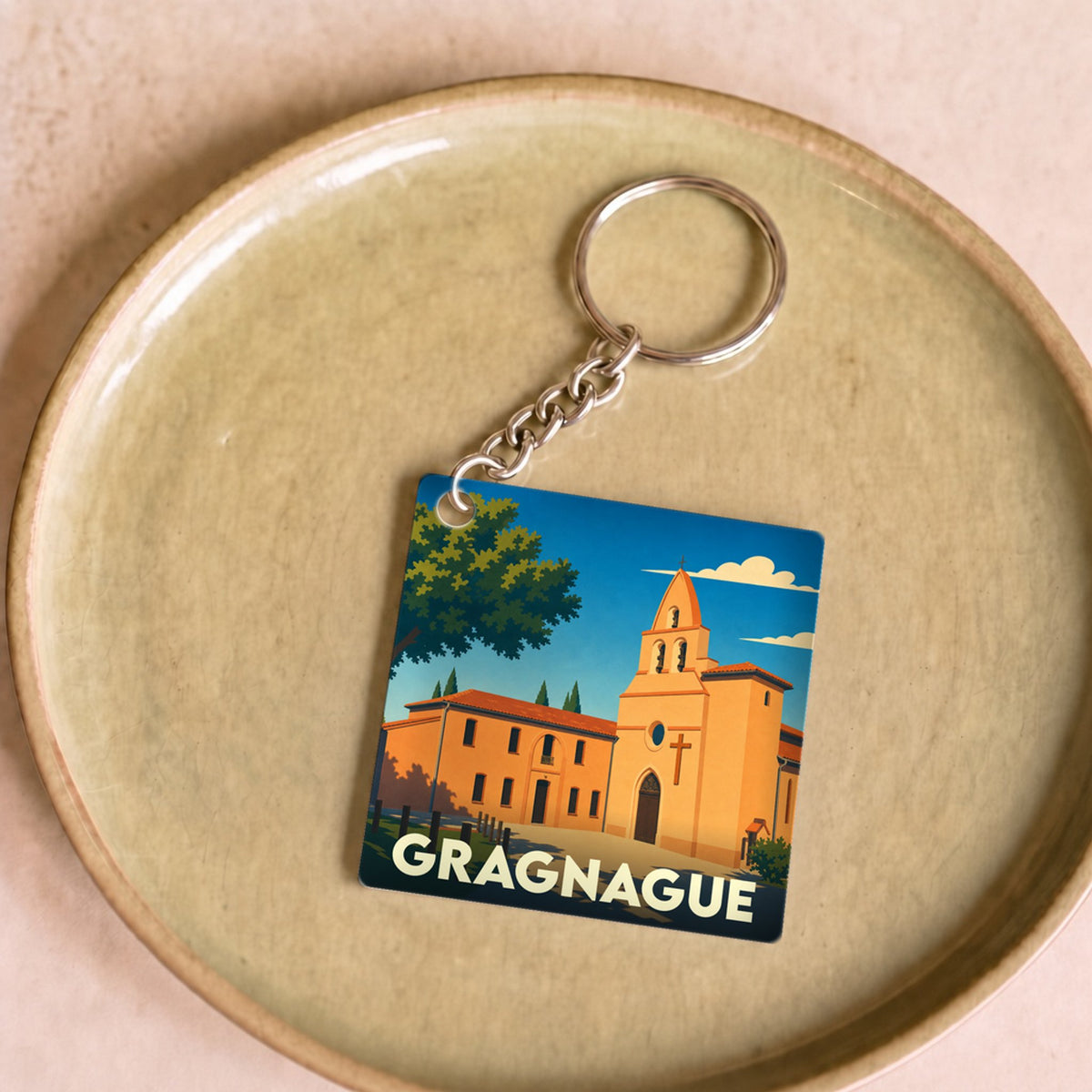 Porte-clés souvenir de la ville de Gragnague avec une illustration stylisée de son église.