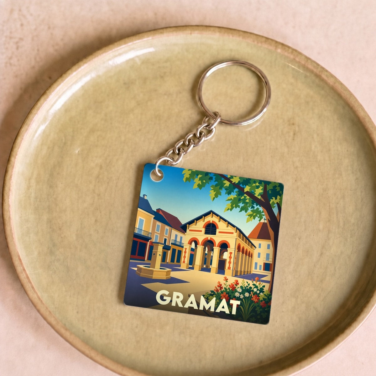 Porte-clés souvenir de la ville de Gramat avec une illustration colorée et stylisée de son architecture.
