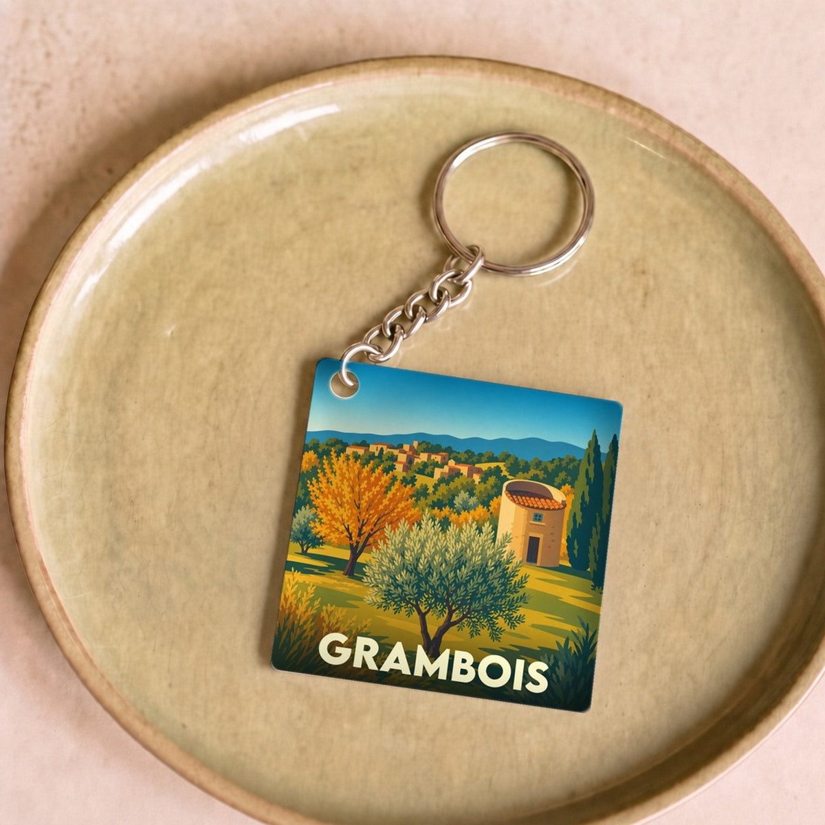 Porte-clés souvenir de la ville de Grambois avec une illustration stylisée d'un paysage provençal.