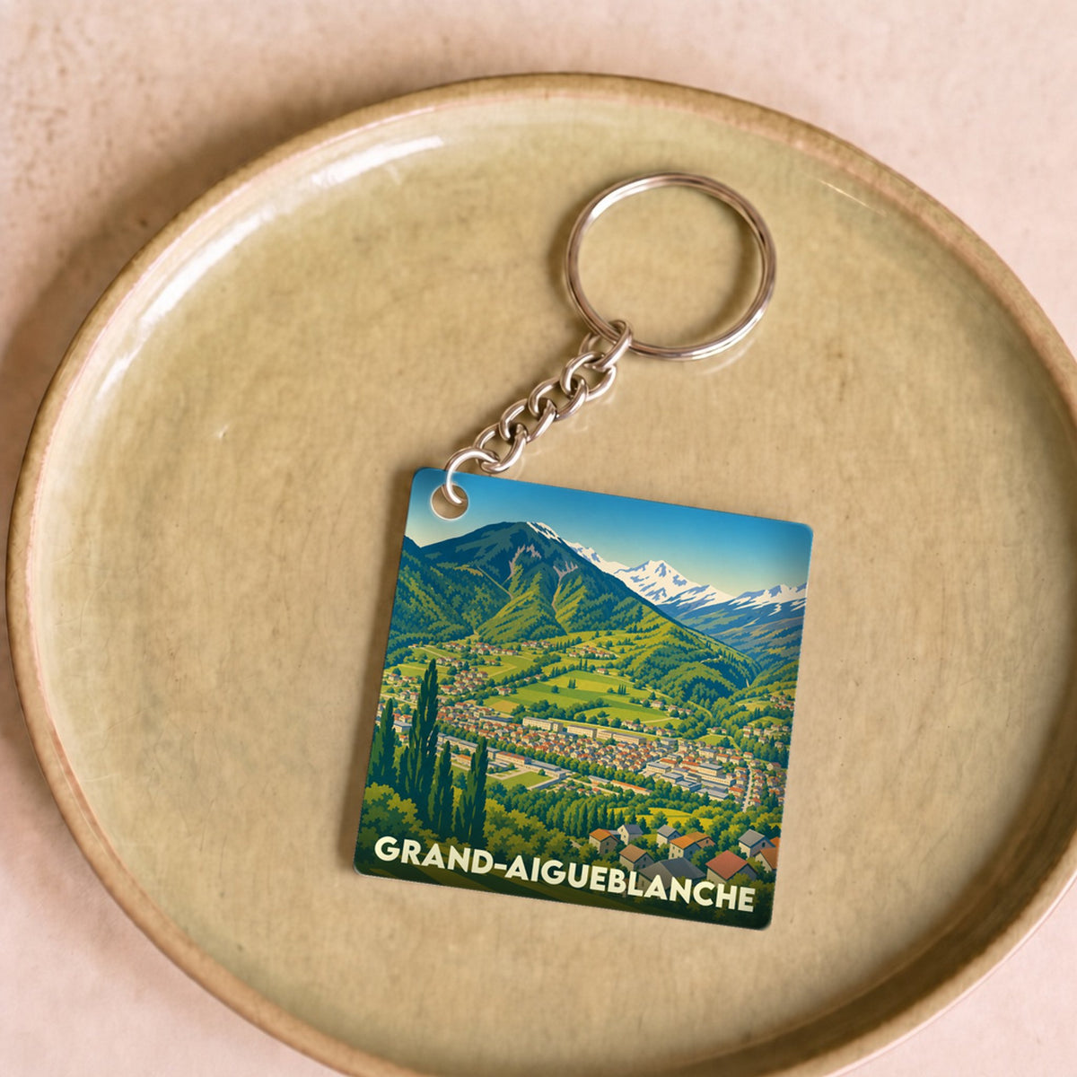 Porte-clés souvenir de la ville de Grand-Aigueblanche avec une illustration stylisée de montagne.