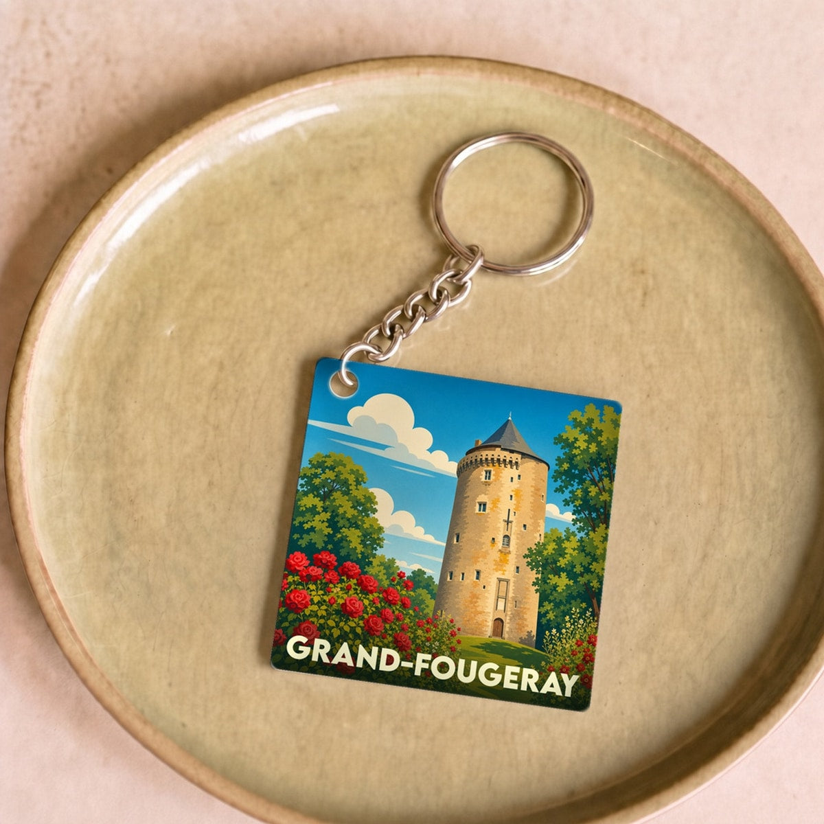 Porte-clés souvenir de la ville de Grand-Fougeray avec une illustration stylisée de sa tour médiévale et de rosiers.