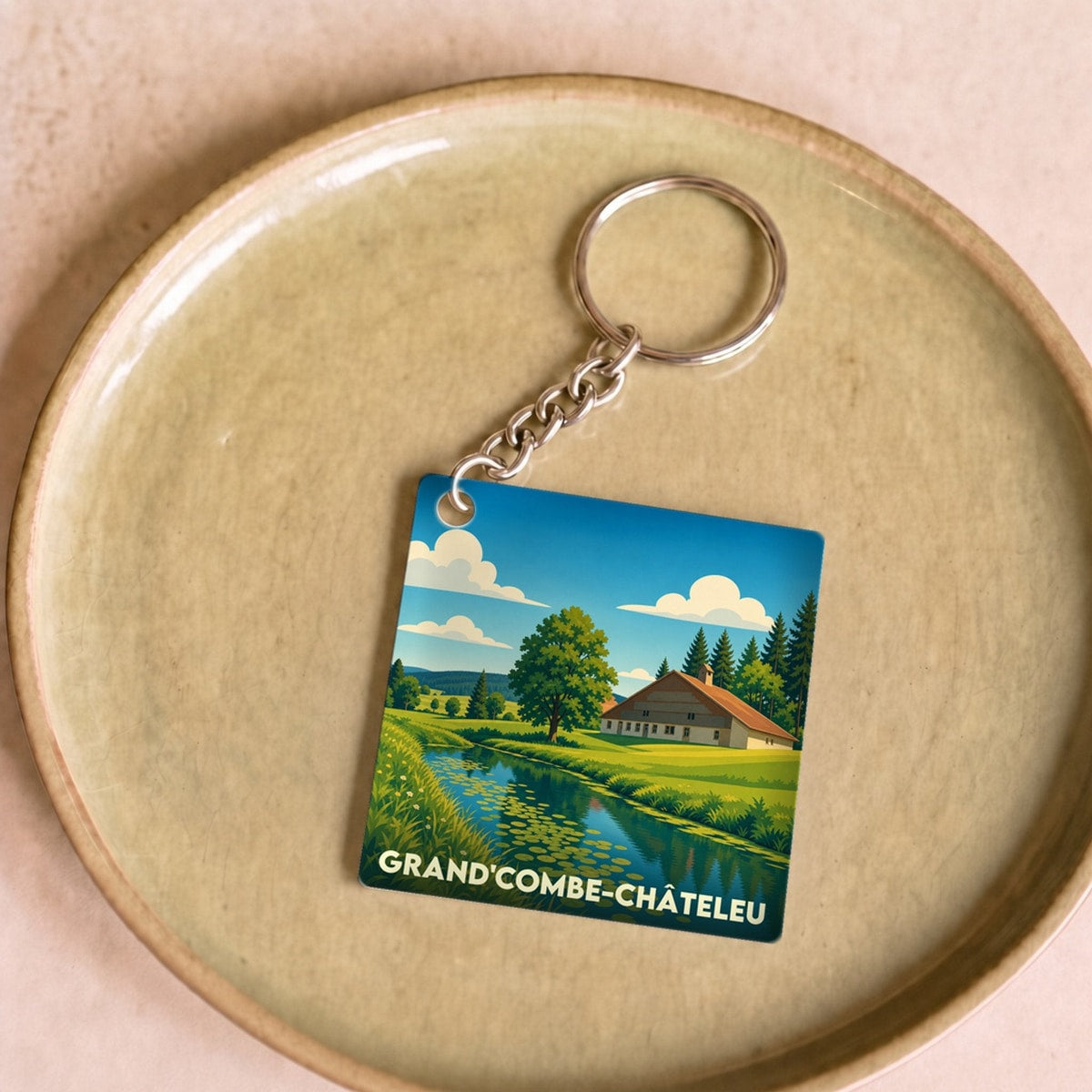 Porte-clés souvenir de la ville de Grand'Combe-Châteleu avec une illustration paysagère stylisée.