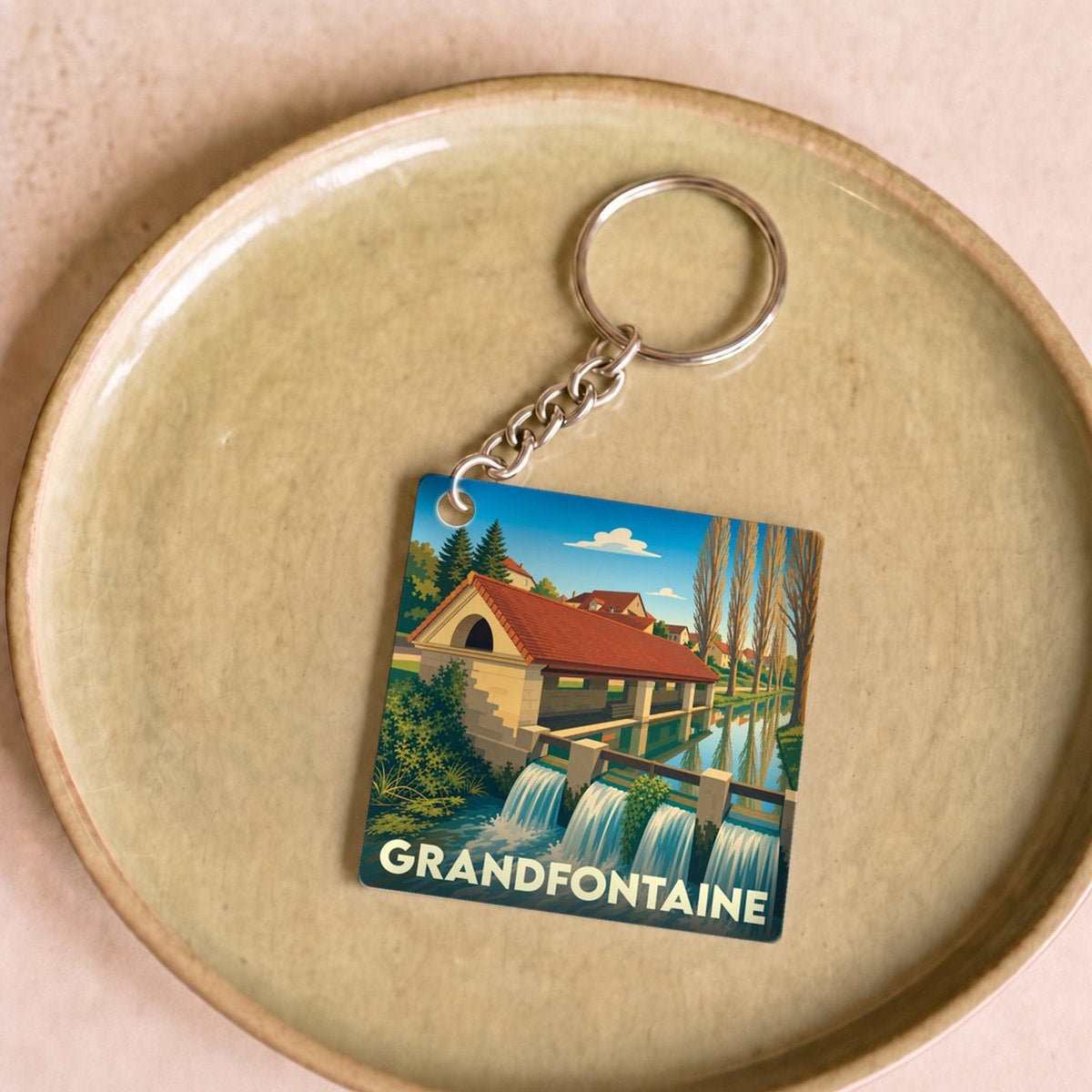 Porte-clés souvenir de la ville de Grandfontaine avec une illustration stylisée.