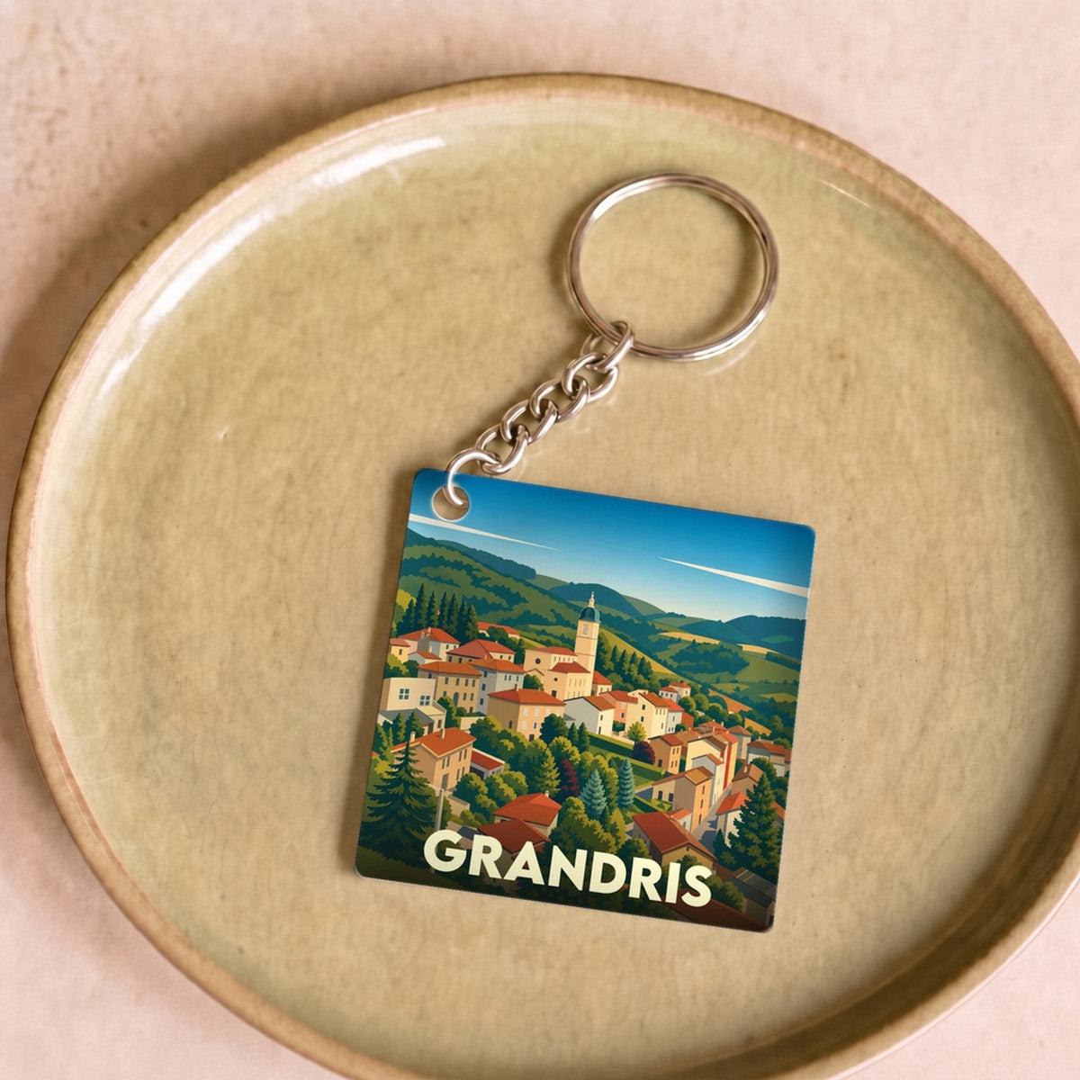 Porte-clés souvenir de la ville de Grandris avec une illustration stylisée de son paysage vallonné.