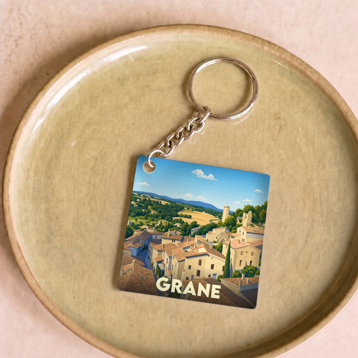 Porte-clés souvenir de la ville de Grane avec une illustration stylisée d'un village perché.
