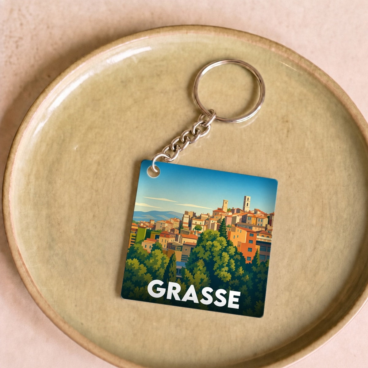 Porte-clés souvenir de la ville de Grasse avec une illustration stylisée.